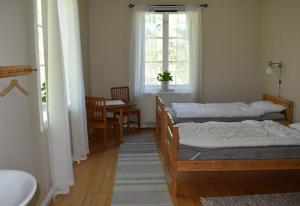 a bedroom with two beds and a table and a window at Vandrarhemmet Gammelgården in Bengtsfors