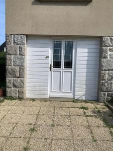 un garaje con una puerta blanca y una pared de piedra en Appartement proche Saint Malo, en Saint-Jouan-des-Guérets