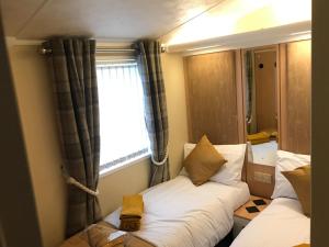 ein kleines Zimmer mit 2 Betten und einem Fenster in der Unterkunft Hot Tub Accommodation North Wales Caravan in Rhyl