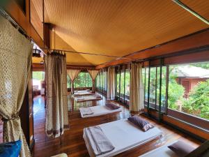 a room with three beds and a large window at Coral Bungalows in Haad Rin