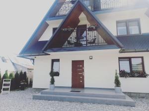 uma casa branca com uma varanda e uma porta em Apartamenty Cichy Kącik em Poronin