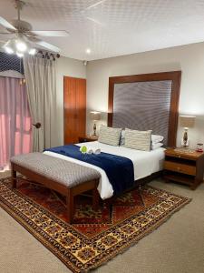a bedroom with a large bed with a blue comforter at Castello Guest House, Bloemfontein in Bloemfontein
