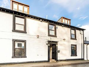 a white house with black windows on a street at The Golden Crown in Tarbolton