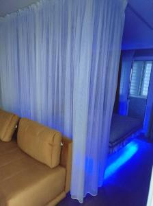 - un canapé dans une chambre dotée de rideaux blancs et d'une fenêtre dans l'établissement Уютная люкс квартира в центре, à Uralsk