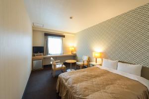 une chambre d'hôtel avec un lit, une table et des chaises dans l'établissement HOTEL LiVEMAX Kofu, à Kai