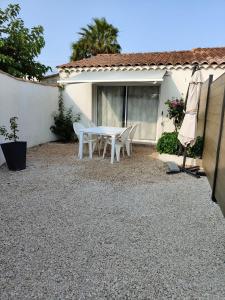 une terrasse avec une table et des chaises blanches en face d'une maison dans l'établissement Cocon en Provence, à Marignane