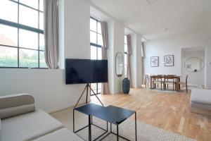 a living room with a couch and a tv on a wall at Cozy and Bright Apartments with Private Car Park in Copenhagen