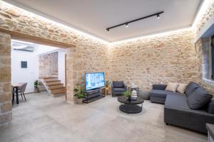 a living room with a stone wall and a tv at FLOR28 STONE HOUSE in Heraklio