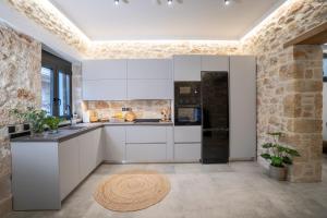 a kitchen with white cabinets and a brick wall at FLOR28 STONE HOUSE in Néa Alikarnassós