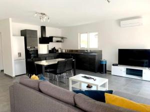 a living room with a couch and a kitchen at Le Brasil - Maison 74 m - Calme avec terrasse Sud classée 3 étoiles in Le Boulou