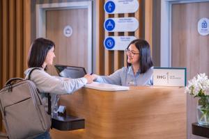 two women shaking hands at a reception desk at Holiday Inn Express - Yerevan, an IHG Hotel in Yerevan