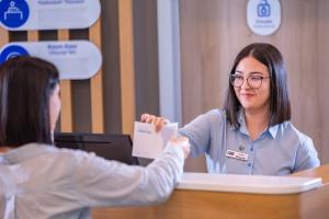 a woman handing another woman a piece of paper at Holiday Inn Express - Yerevan, an IHG Hotel in Yerevan