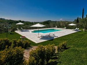 a pool with chairs and umbrellas in a yard at Cosy holiday home in Selci with swimming pool in Selci