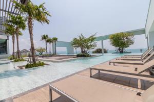 a swimming pool with benches and palm trees in a building at Aeras beachfront 1 bedroom in Jomtien Beach