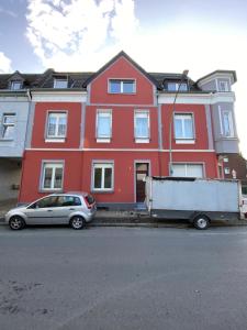 a red house with a silver car parked in front of it at SUPERIOR! Nespresso - Küche - Prime - Parkplatz in Duisburg