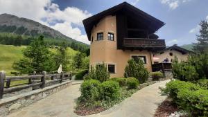 a large house with a fence next to a mountain at Chalet Rin da Pemont in Livigno