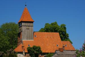 un edificio con techo naranja y torre en Ferienwohnung Schwalbennest - a89292, en Garz
