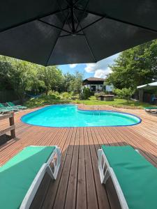 uma piscina com um guarda-sol num deque de madeira em Lavender and Poppy cottages em Bebrovo