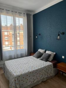 1 dormitorio con 1 cama con pared azul en Douai 2: joli appartement face à la gare, en Douai