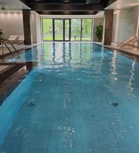 a swimming pool with blue water in a building at CHILLIapartamenty - Wyspa Solna - RIVER in Kołobrzeg