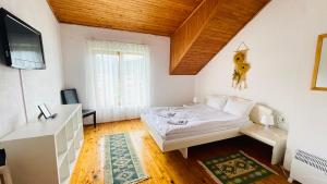 a bedroom with a bed and a desk and a television at Vila Kira Buşteni in Buşteni