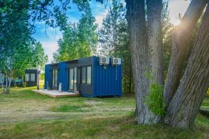 een blauw tiny house in een park naast een boom bij Arche Siedlisko Rogacze 65 in Milejczyce