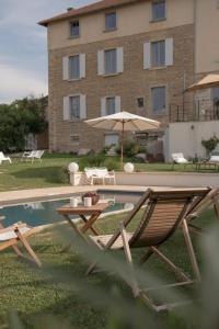a pool with two chairs and a table and an umbrella at La Maison des Monts d'Or in Saint-Germain-au-Mont-dʼOr