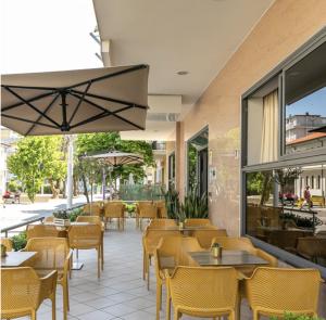 ベッラーリア・イジェア・マリーナにあるHotel Atlanticのテーブルと椅子、パティオ付きのレストラン