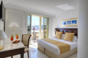 a bedroom with a bed and a desk and a table and chair at Hôtel West End Promenade in Nice