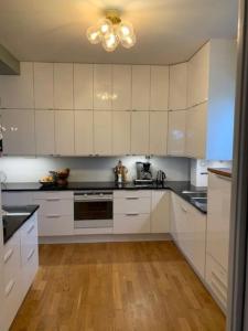a kitchen with white cabinets and a ceiling fan at Stort hus i Stockholm in Sollentuna