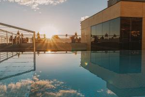 a swimming pool in front of a building with the sunset at Hotel Split in Podstrana