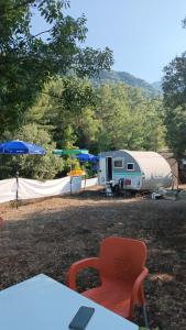 einen Campingplatz mit einem Wohnmobil, einem Zelt und einem Regenschirm in der Unterkunft Es&Es campıng ve bungalov in Köyceğiz