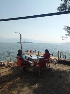 two people sitting at a table near the water at Es&Es campıng ve bungalov in Köyceğiz