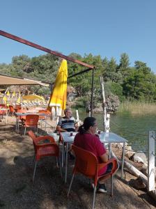 two people sitting at tables by the water at Es&Es campıng ve bungalov in Köyceğiz