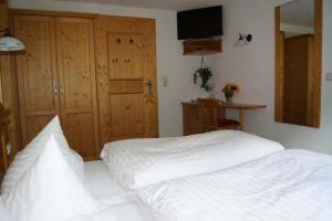 a bedroom with a white bed and a television at Apartpension Schollberg in Sankt Anton am Arlberg