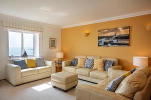 a living room with two couches and a couch at Marine Point, Mevagissey - sensational cliff top views of harbour and bay in Mevagissey