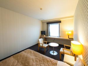 a hotel room with a bed and a table and chairs at HOTEL LiVEMAX Kofu in Kai