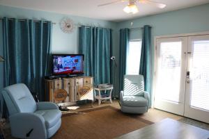 sala de estar con cortinas azules y TV en Dunesberry, en Gulf Shores