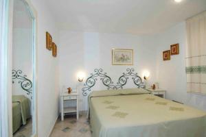 a white bedroom with a bed and two tables at Sardegna Beach Cala Reale in Santa Marinella