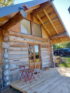 eine Hütte mit 2 Stühlen und einem Tisch auf einer Veranda in der Unterkunft Les Petites Fustes Dans La Prairie in Coucouron