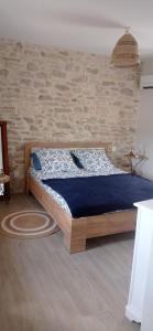 een bed in een kamer met een bakstenen muur bij Sous le Tilleul in Saint-Maurice-de-Cazevieille