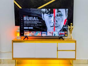 un televisor en la parte superior de un tocador con un cartel de película en Cozy Apartment - Hideaway with 5G WiFi, en Abuja