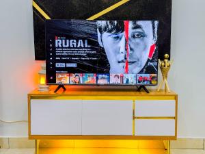 a television on top of a dresser with a movie poster at Cozy Apartment - Hideaway with 5G WiFi in Abuja