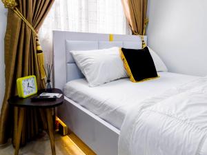 un letto bianco con un cuscino nero e giallo di Cozy Apartment - Hideaway with 5G WiFi ad Abuja