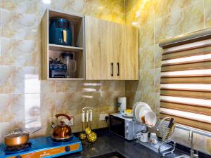 cocina con armarios de madera y encimera en Cozy Apartment - Hideaway with 5G WiFi en Abuja