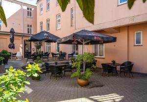 un patio al aire libre con mesas, sillas y sombrillas en Hotel Postgaarden, en Fredericia