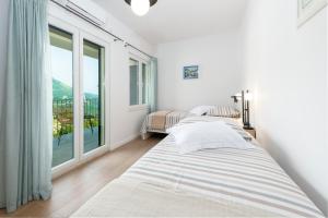 two beds in a room with a large window at Holiday home Perko in Dunave Krajnje