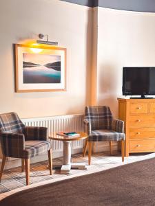 a living room with two chairs and a tv at The Glen Mhor Apartments in Inverness