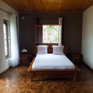 a bedroom with a white bed with a window at Andasibe Sifaka Lodge in Andasibe