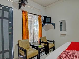 a bedroom with two chairs and a bed and a window at OYO 92579 Hotel Mutiara in Pematangsiantar